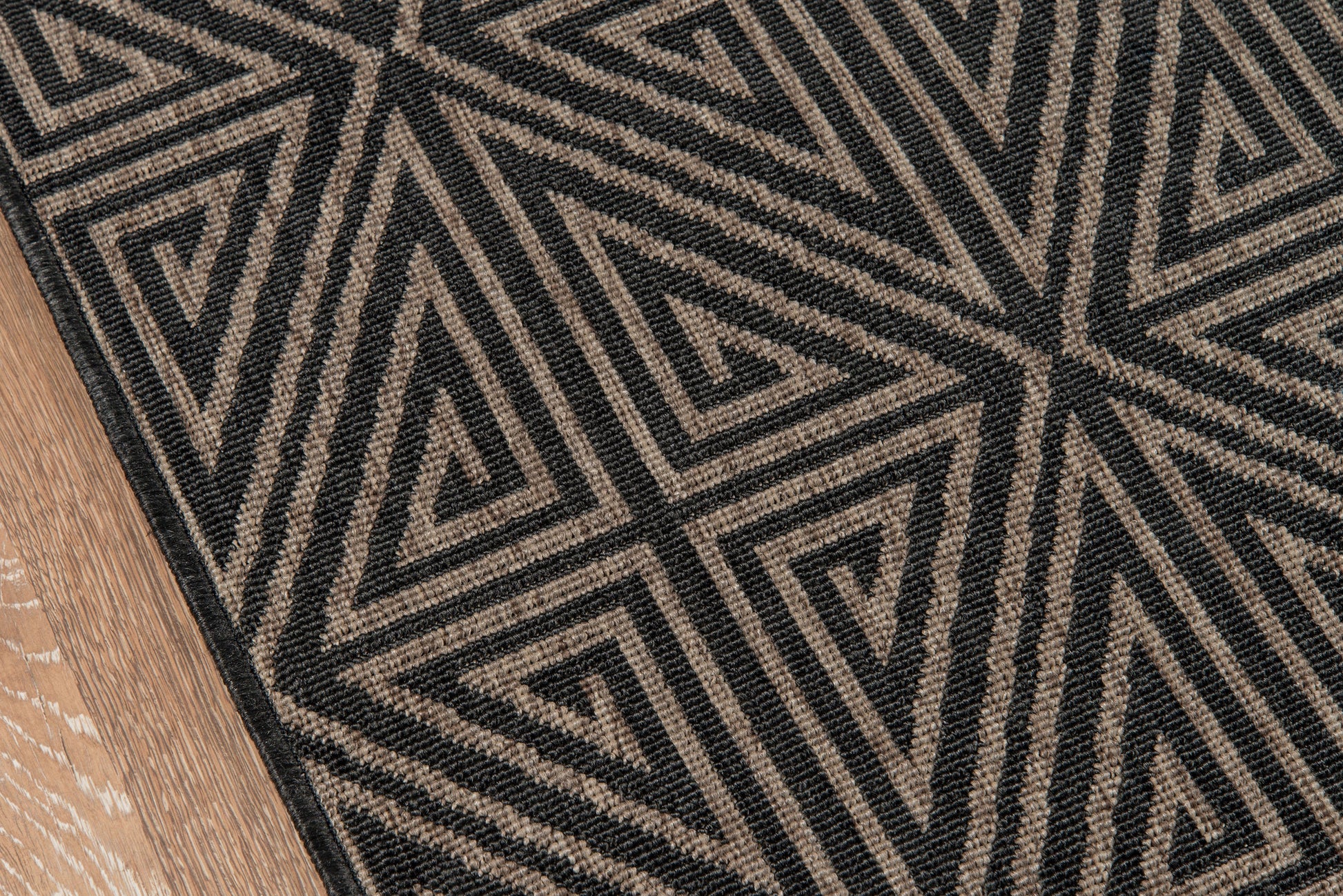 Textured bold black and natural beige geometric rug with triangular patterns on a wooden floor.