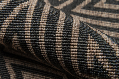 Close-up of a black and beige woven rug with geometric chevron pattern and textured fibers.