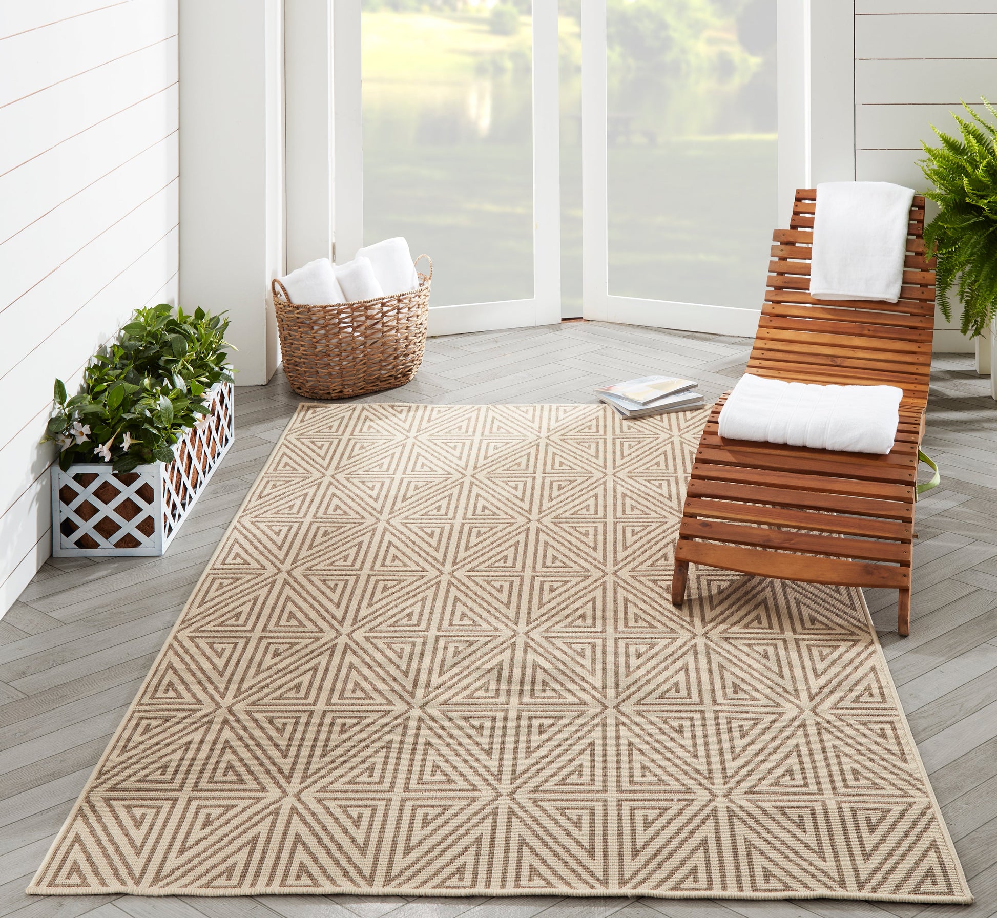 Beige geometric rug on light wood floor with wicker basket, potted plants, and wooden slat lounge chair with white towels.