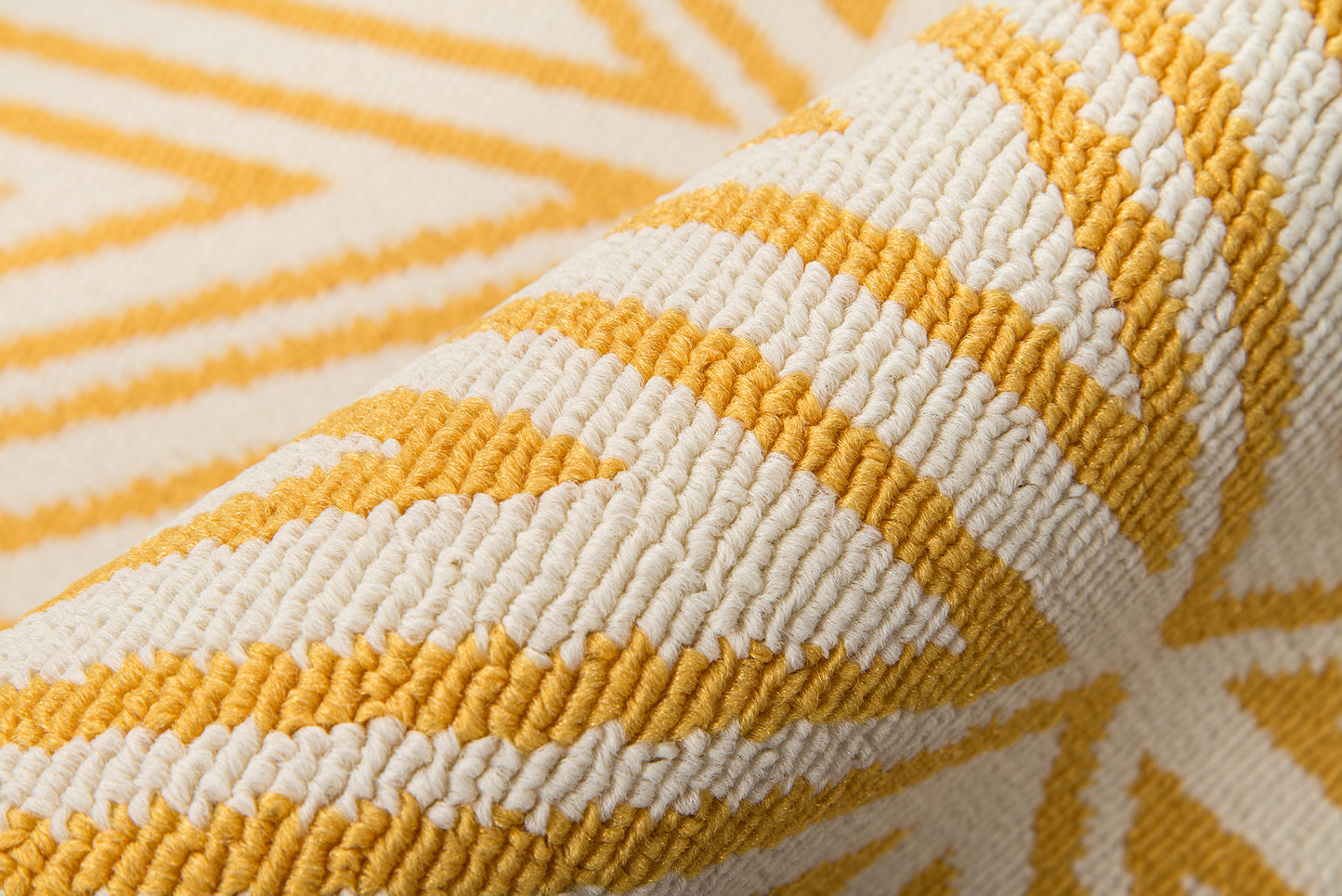 Close-up of a yellow and ivory woven rug with chunky yarn and chevron geometric pattern.