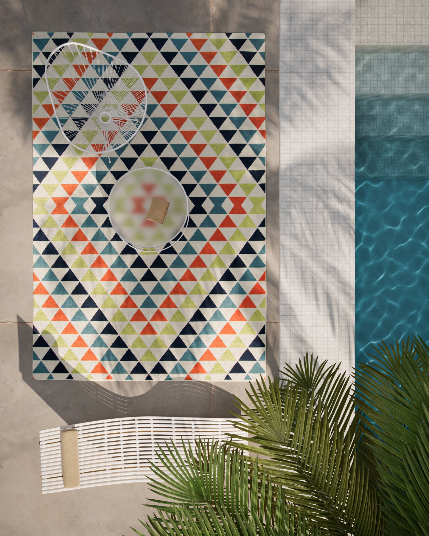 Baja-inspired outdoor rug with multicolor triangle pattern by the pool; navy, teal, lime, and orange.