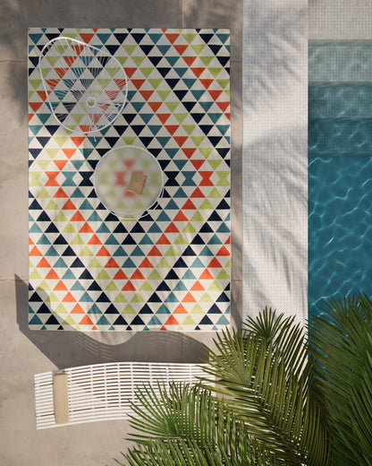 Baja-inspired outdoor rug with multicolor triangle pattern by the pool; navy, teal, lime, and orange.