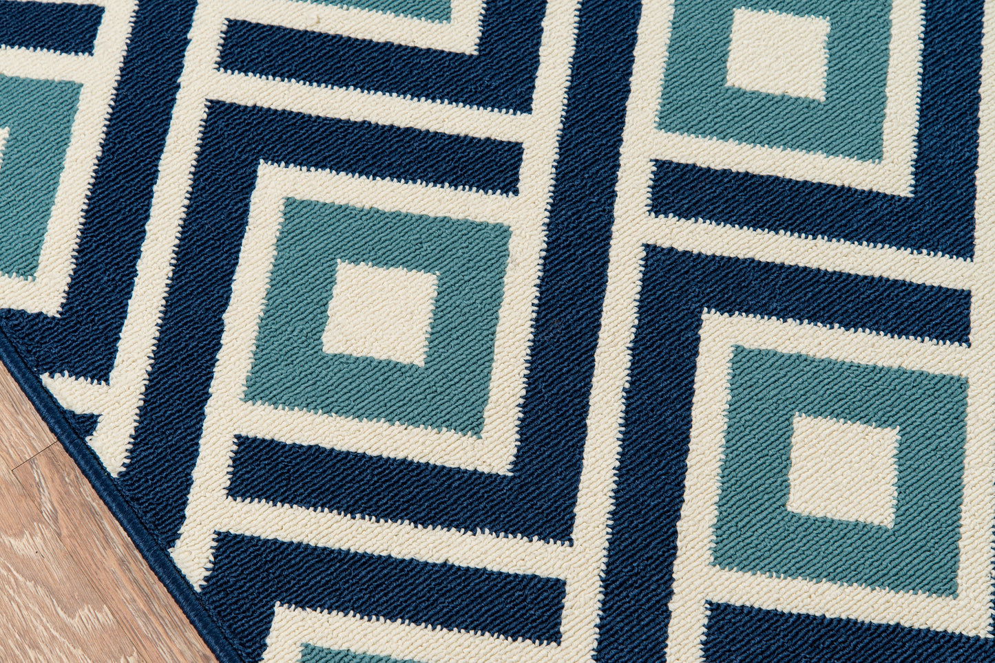 Geometric woven area rug in teal, navy and ivory with square-in-square Greek-key pattern; modern living room rug.