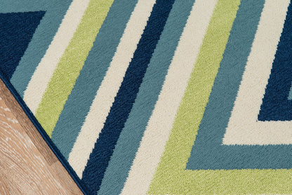 Close-up of chevron striped rug featuring blue, teal, lime green and cream with navy border on wood floor.