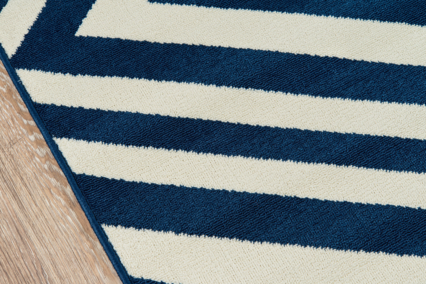 Navy and cream striped rug with thick boucle pile, diagonal view on wooden floor.