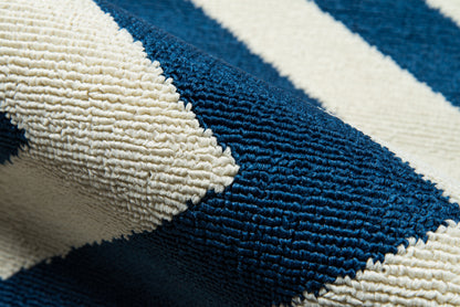 Close-up of a plush striped rug with navy blue and ivory cream looped pile.