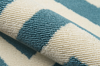 Close-up of teal and cream woven rug with thick looped texture and bold geometric stripes.