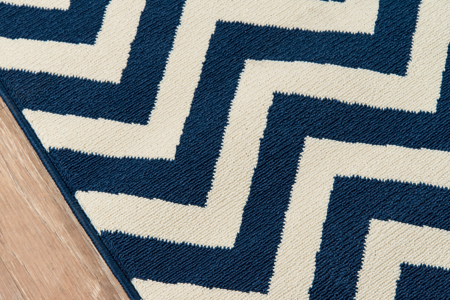 Navy and ivory zigzag rug with Greek-key maze pattern on wood floor; woven textile.