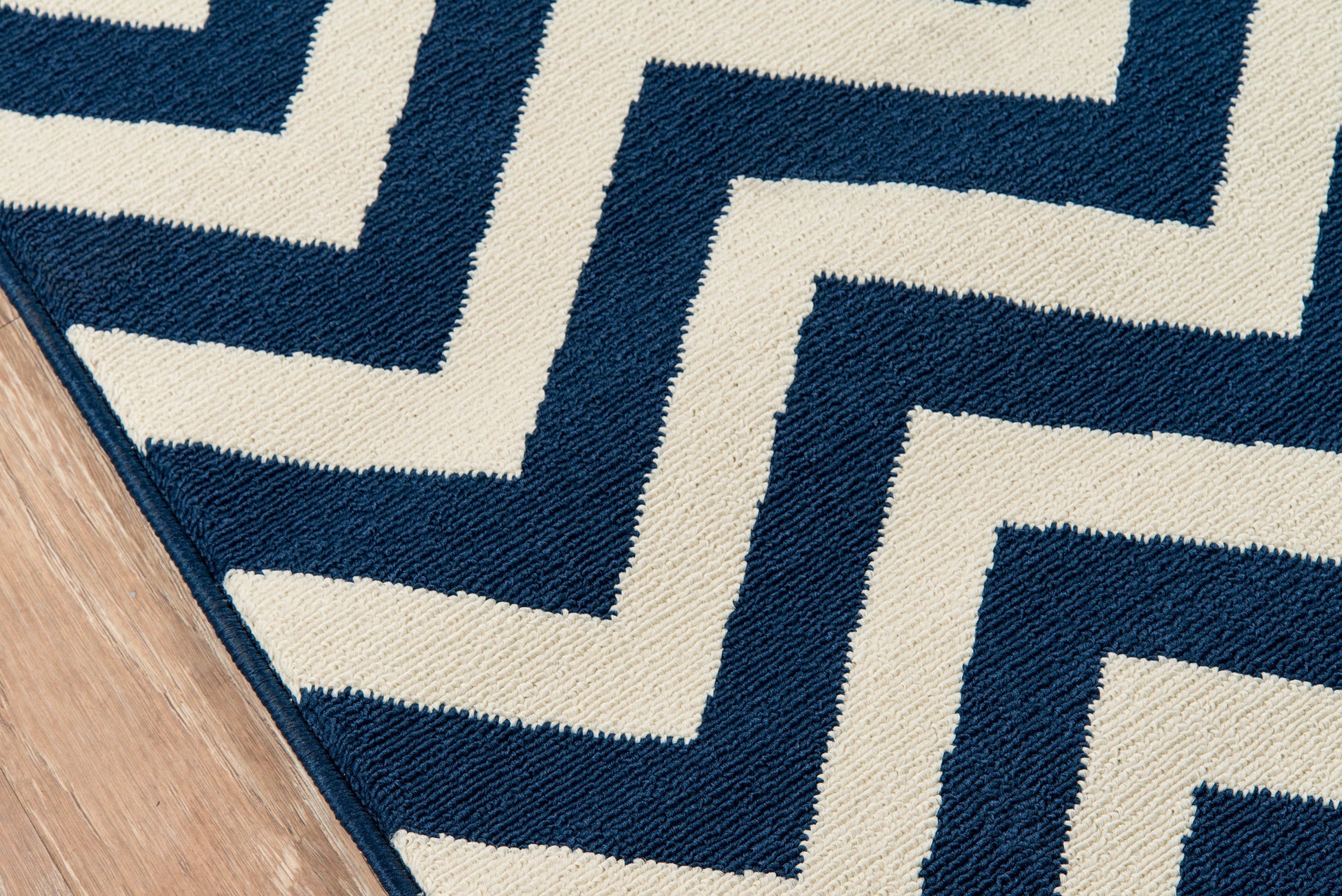 Navy and ivory zigzag rug with Greek-key maze pattern on wood floor; woven textile.