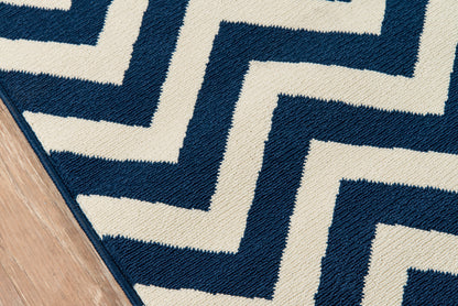 Navy and ivory zigzag rug with Greek-key maze pattern on wood floor; woven textile.