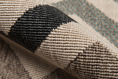 Close-up of a chunky woven rug in beige, black and brown with geometric diamond motif and textured loops.