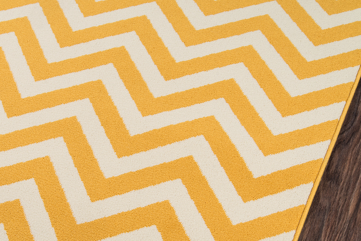 Bright yellow and ivory chevron rug with zigzag pattern on wood floor.
