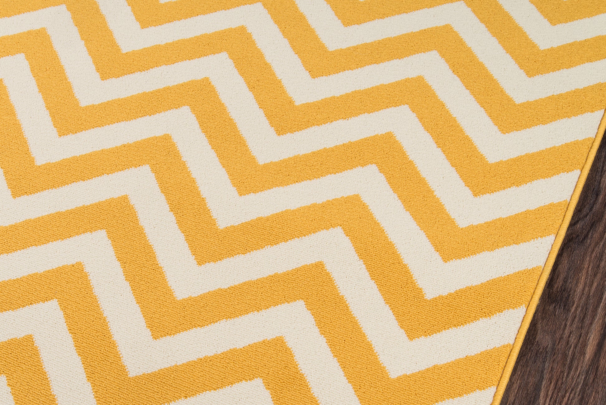 Bright yellow and ivory chevron rug with zigzag pattern on wood floor.