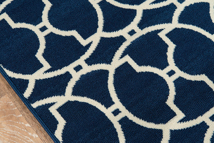 Navy blue rug with white circular geometric pattern; edge on a wooden floor.