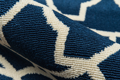Navy blue woven rug with bold white geometric zigzag pattern and textured weave.