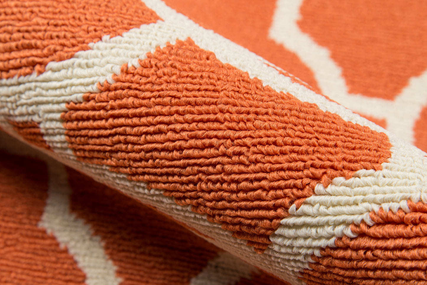Close-up of orange and white geometric rug with plush loop pile and textured stripes.
