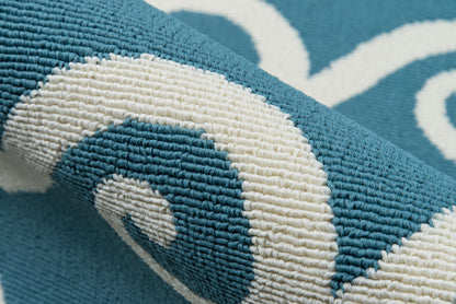 Teal blue rug with white swirl pattern, textured loop pile, rolled edge.