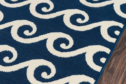 Navy blue rug with white spiral wave pattern; soft textured weave, coastal style, edge on wood floor.