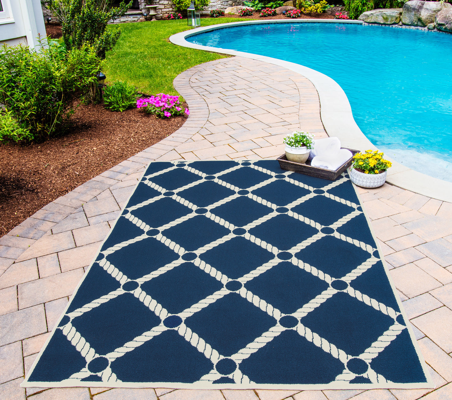 Rectangular navy outdoor rug with white rope lattice pattern on brick pool patio