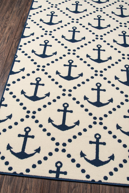 Navy anchor-pattern rug, 7' x 10', on white with dotted diamond borders and blue edge on a wooden floor.