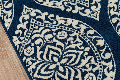 Navy blue and ivory patterned rug with medallion and floral motifs, woven textile with dark edge, on wooden floor.