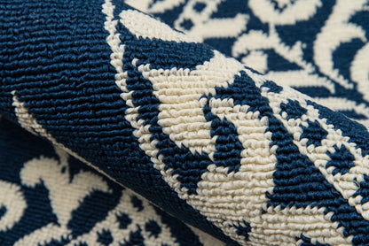 Close-up of navy blue and ivory woven rug with bold scroll pattern and thick loop pile.