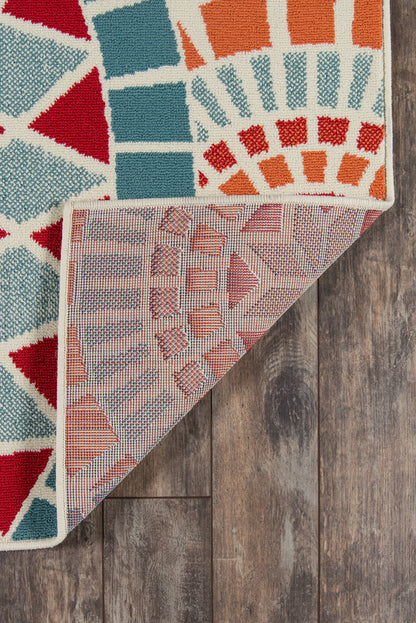 Colorful kilim-style runner rug with bold geometric patterns in red, teal, and orange; folded corner reveals pink underside.