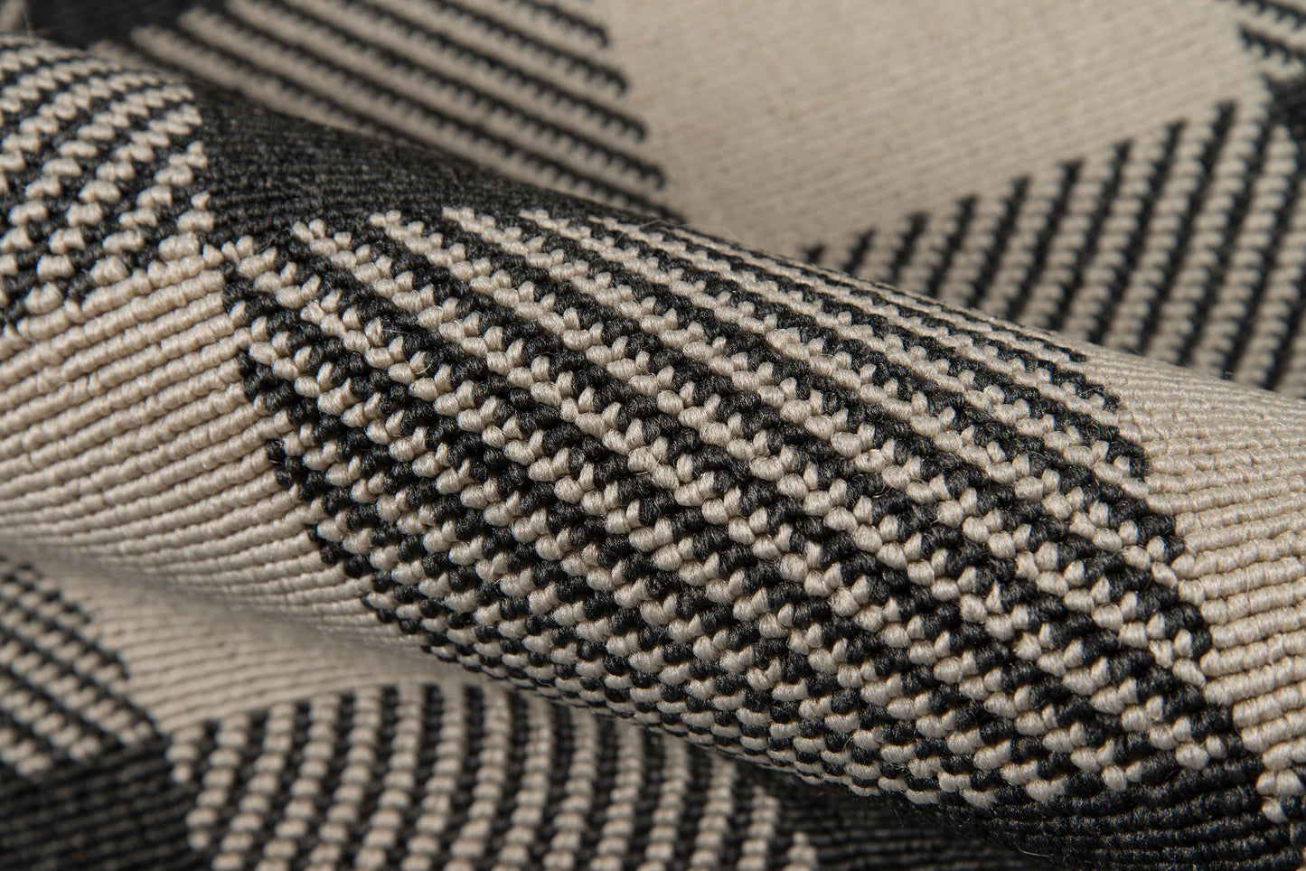 Close-up of beige and black striped woven rug with a textured tweed-like weave; versatile rug.