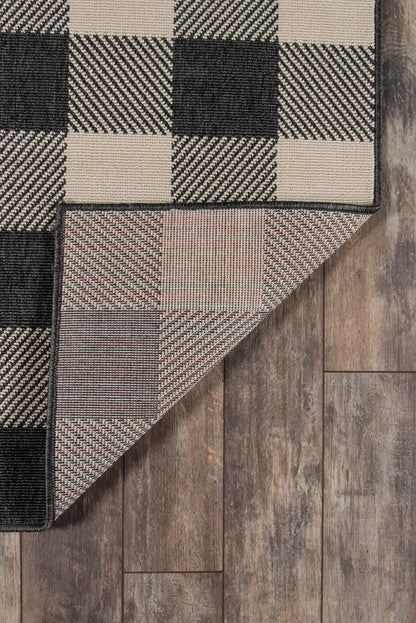 Beige and black checkerboard woven rug with a folded corner exposing the underside on wood flooring.