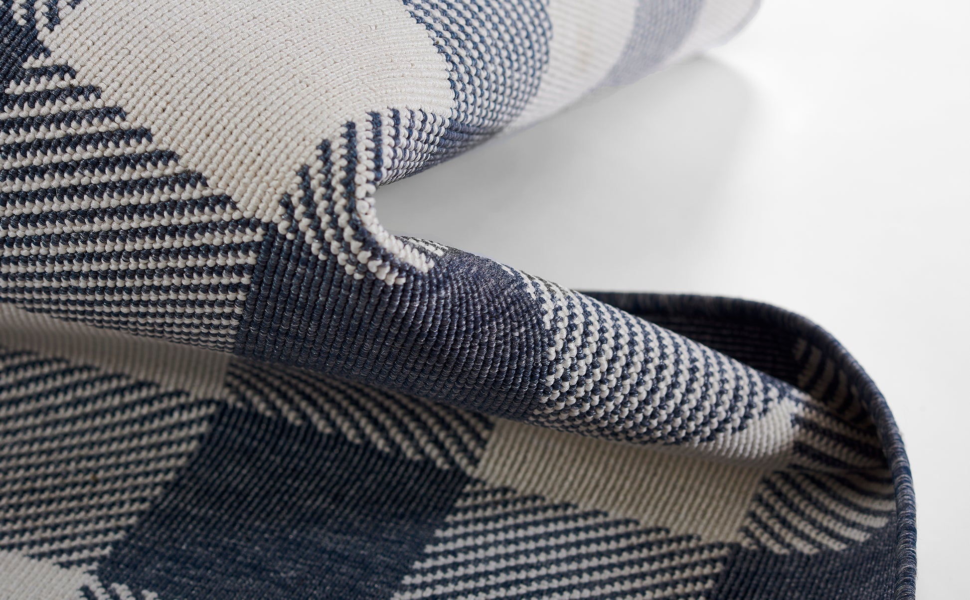 Navy and white plaid woven rug with folded edge and denim-like texture, 8' x 11'.
