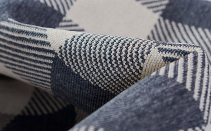Close-up of navy blue and white geometric woven rug, folded.