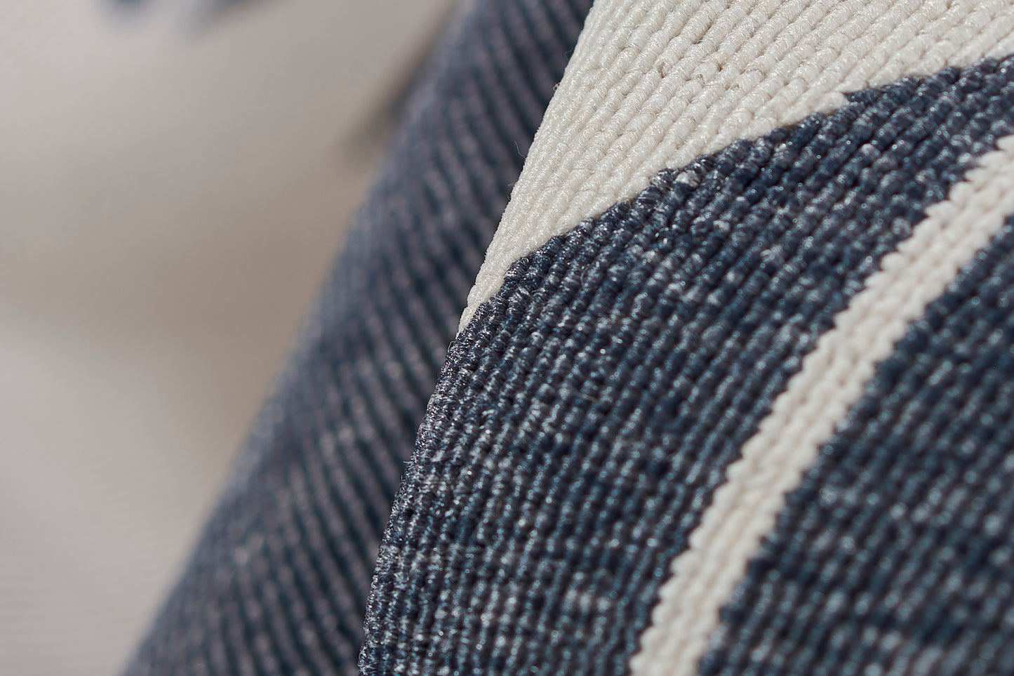 Close-up of dark blue denim with a cream stripe, textured twill weave, ideal for cushions or upholstery.
