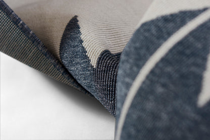 Close-up of blue denim-textured fabric with beige leaf motif; soft cushion upholstery in denim and cream.