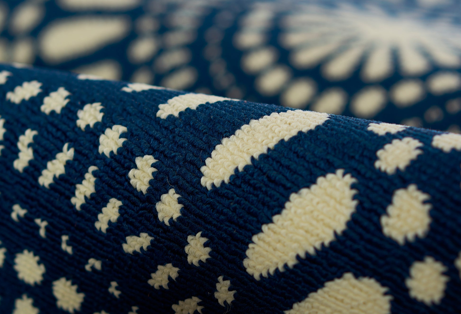 Close-up of navy blue woven throw with ivory geometric dot motif and textured weave.