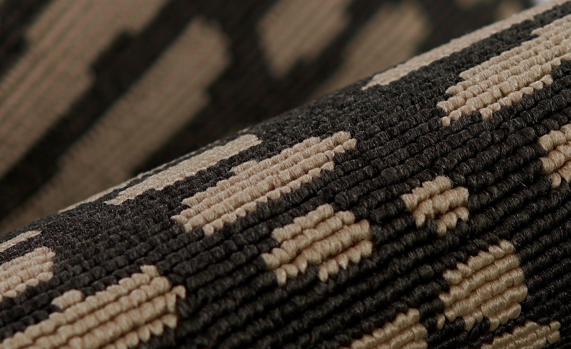 Close-up of a dark brown and tan geometric loop-pile rug with textured tufted pattern.