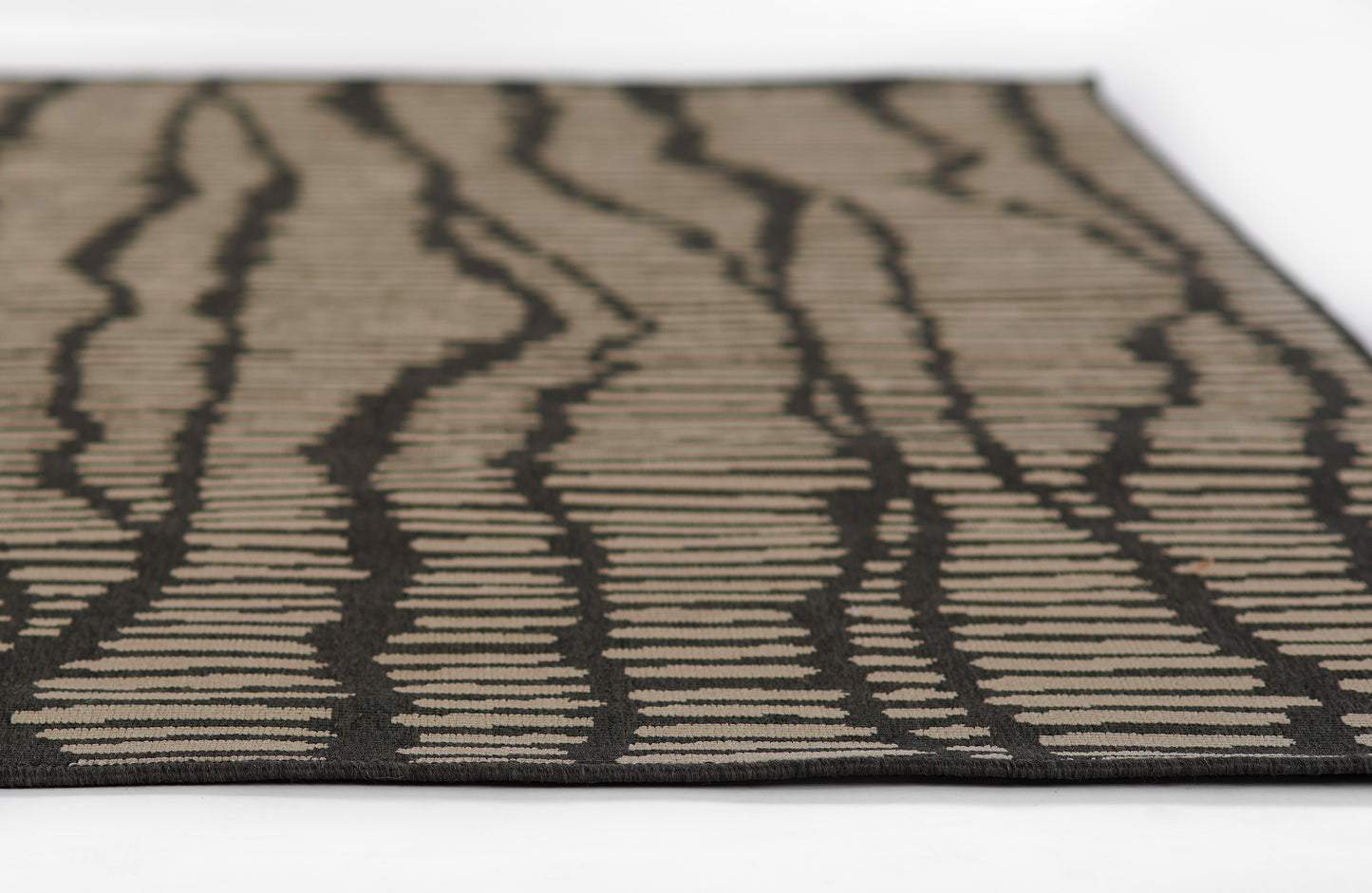 Rectangular Baja-style rug: beige background with bold black zebra-like wavy stripes, low-pile woven texture.