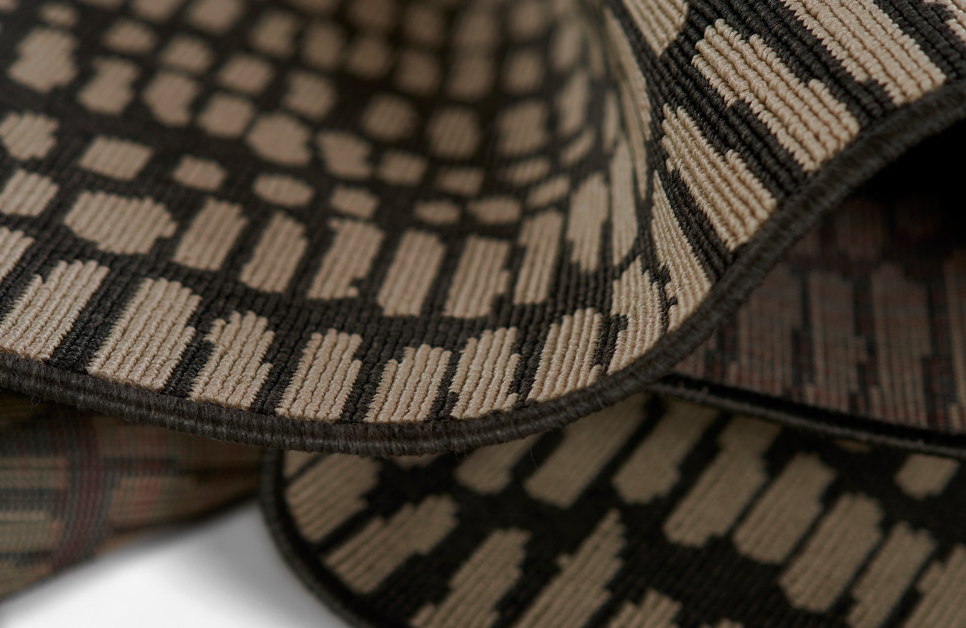 Close-up of a woven rug with brown and beige geometric stripe motif.