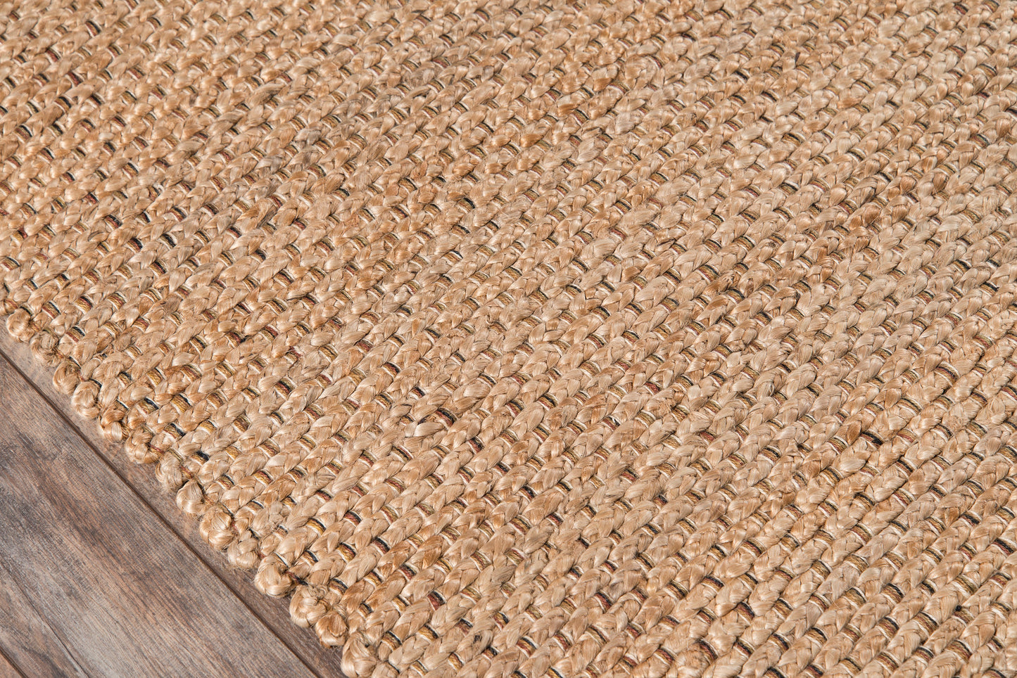 Natural jute woven rug with chunky braided texture on dark wood floor.