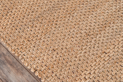 Natural jute woven rug with chunky braided texture on dark wood floor.