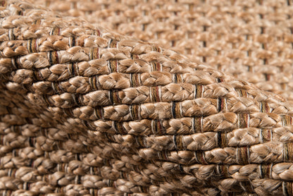 Natural jute braided rug in tan/beige with darker stripe accents; chunky coastal weave.