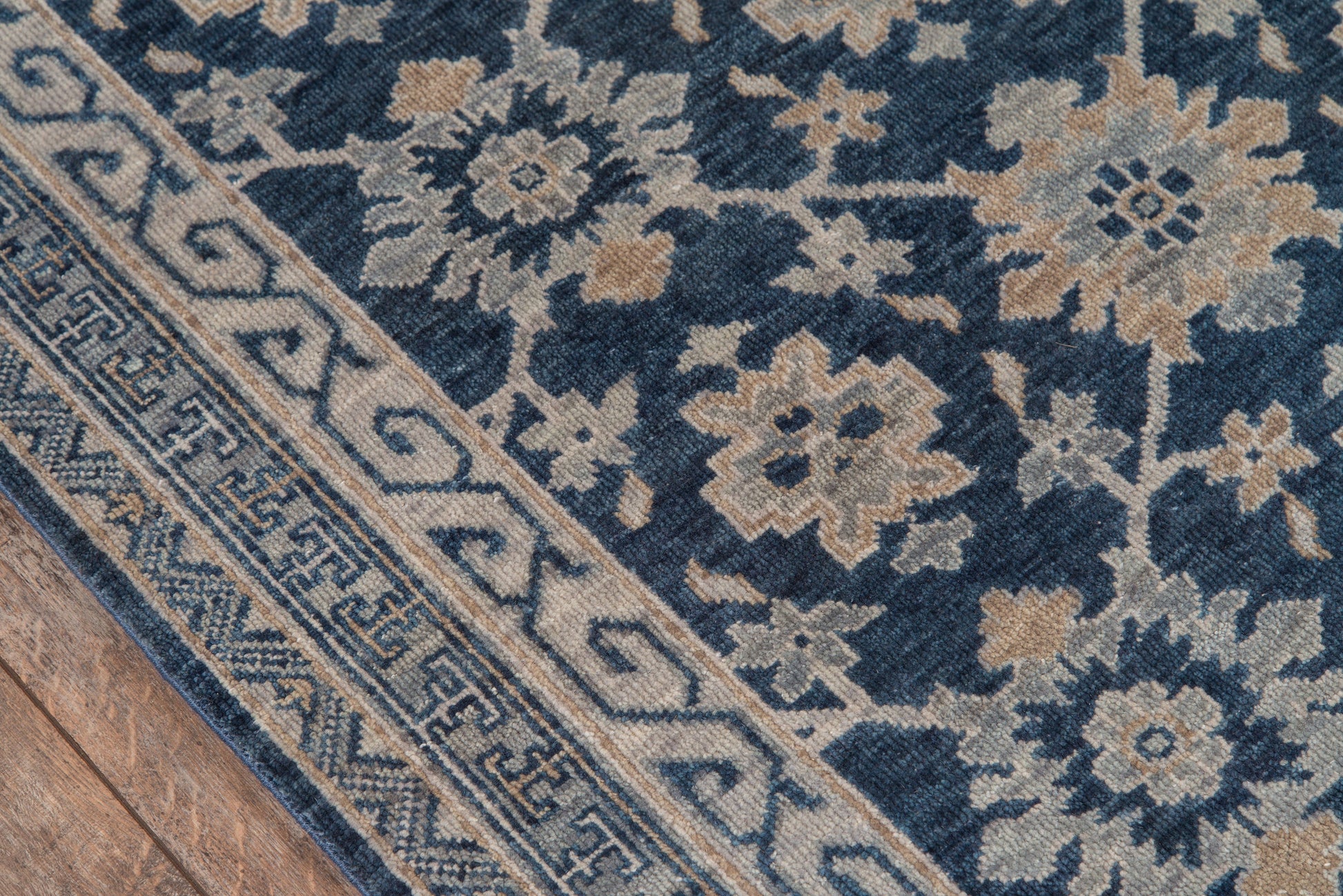 Rectangle blue woven rug with ivory-beige floral motifs and geometric border.
