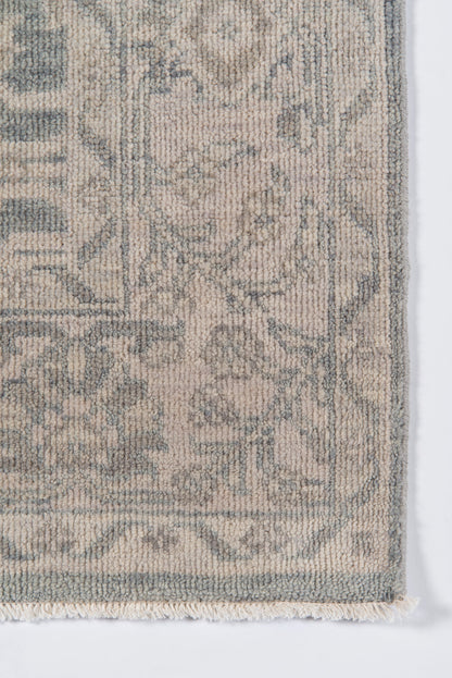 Beige and blue-gray traditional rug with subtle floral medallion pattern, woven pile, fringed edge.