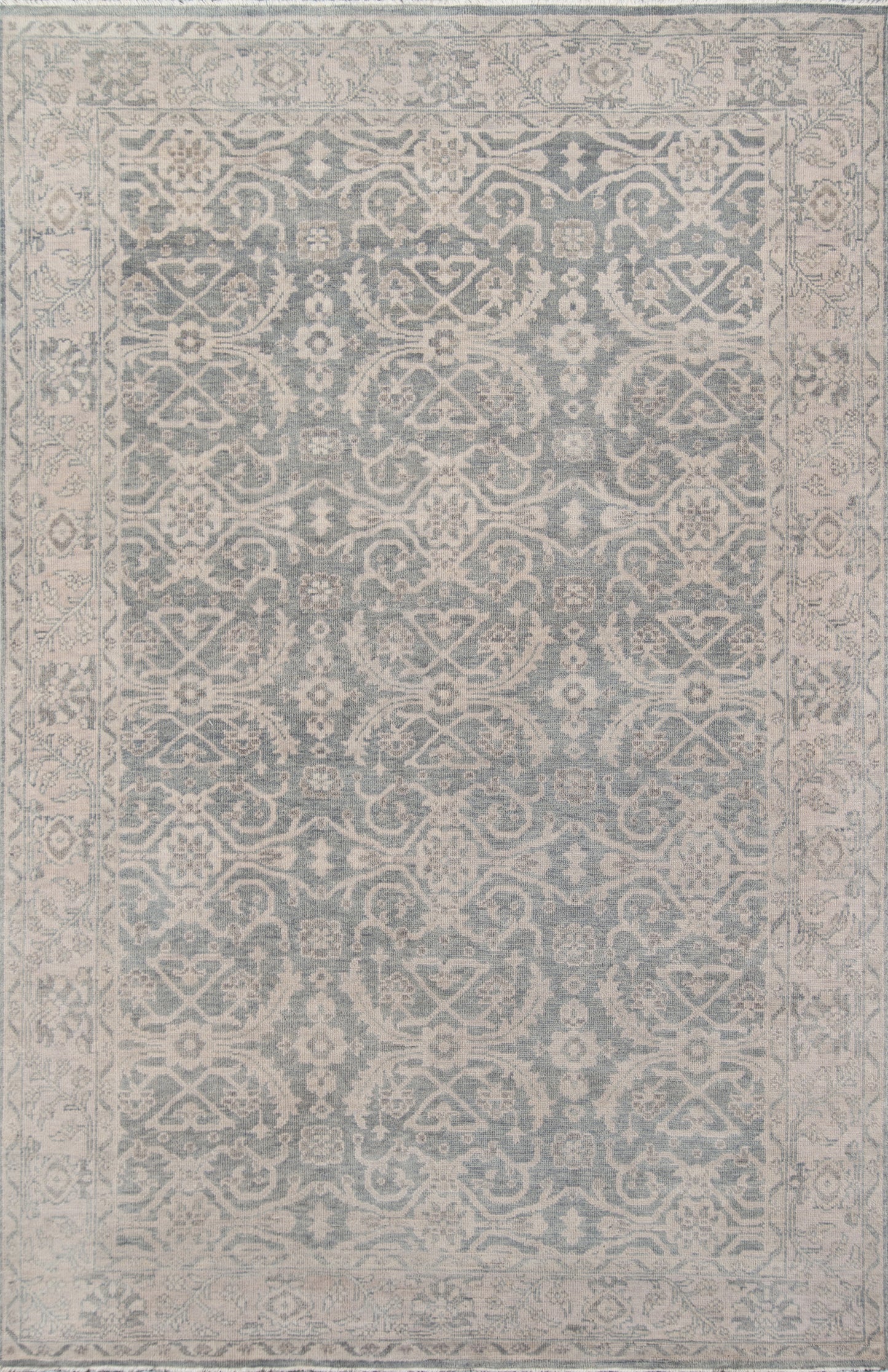 Blue-gray oriental area rug with ivory floral arabesque motifs and a decorative border.