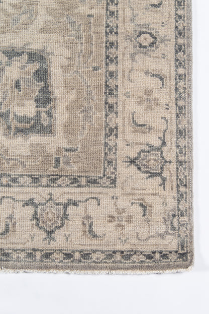 Beige and gray distressed woven rug with blue-gray border and vintage floral-medallion design.