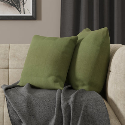 Two olive-green square cushions on a beige sofa with a gray textured throw blanket, modern cozy living room setup.