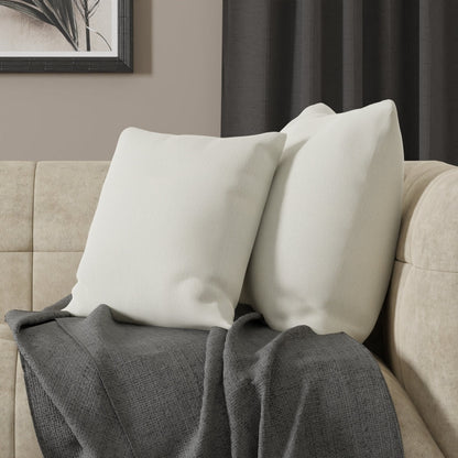 Two cream throw pillows on a beige sofa with a dark gray textured blanket draped over the armrest