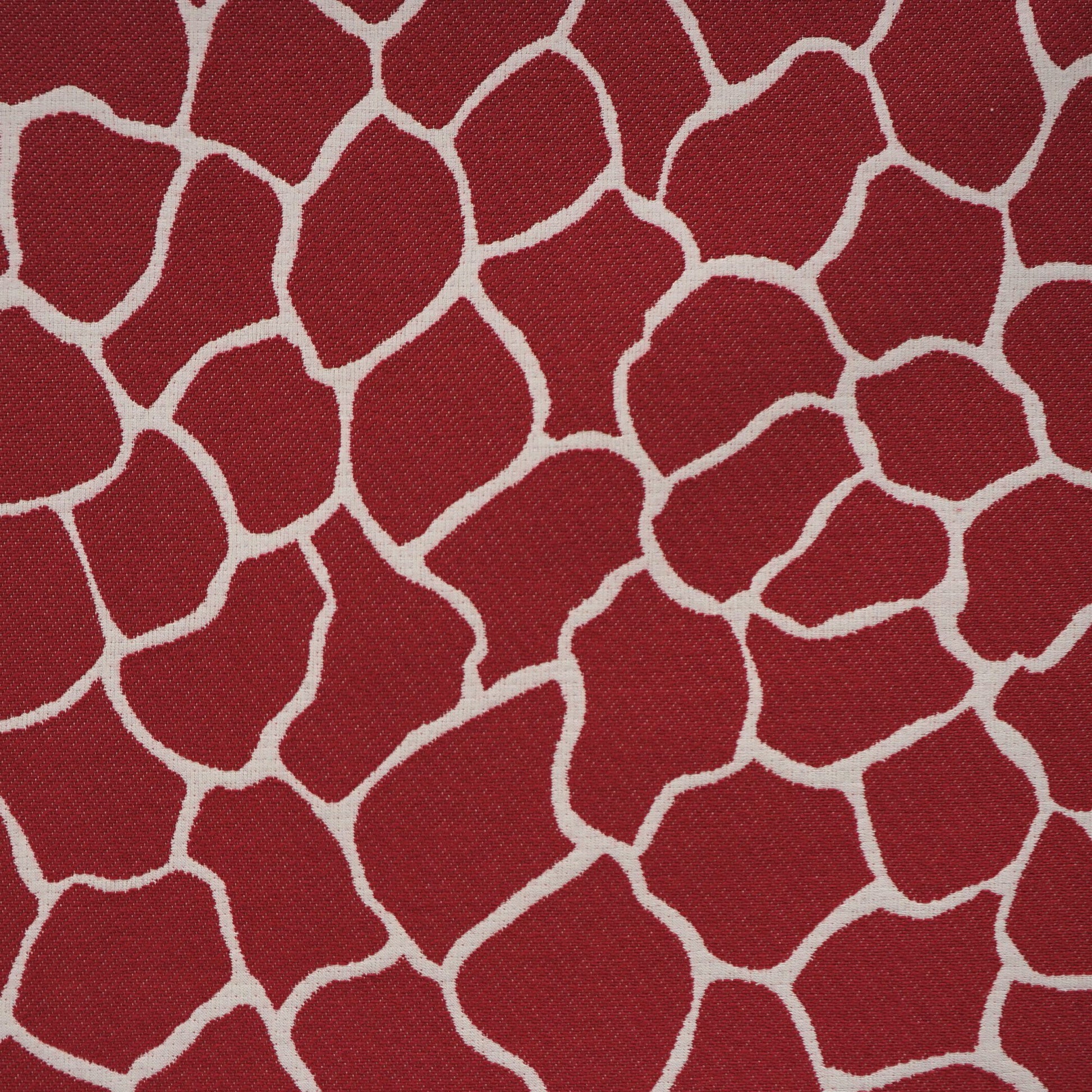 Red woven fabric with irregular white outlines forming a giraffe-like mosaic pattern.