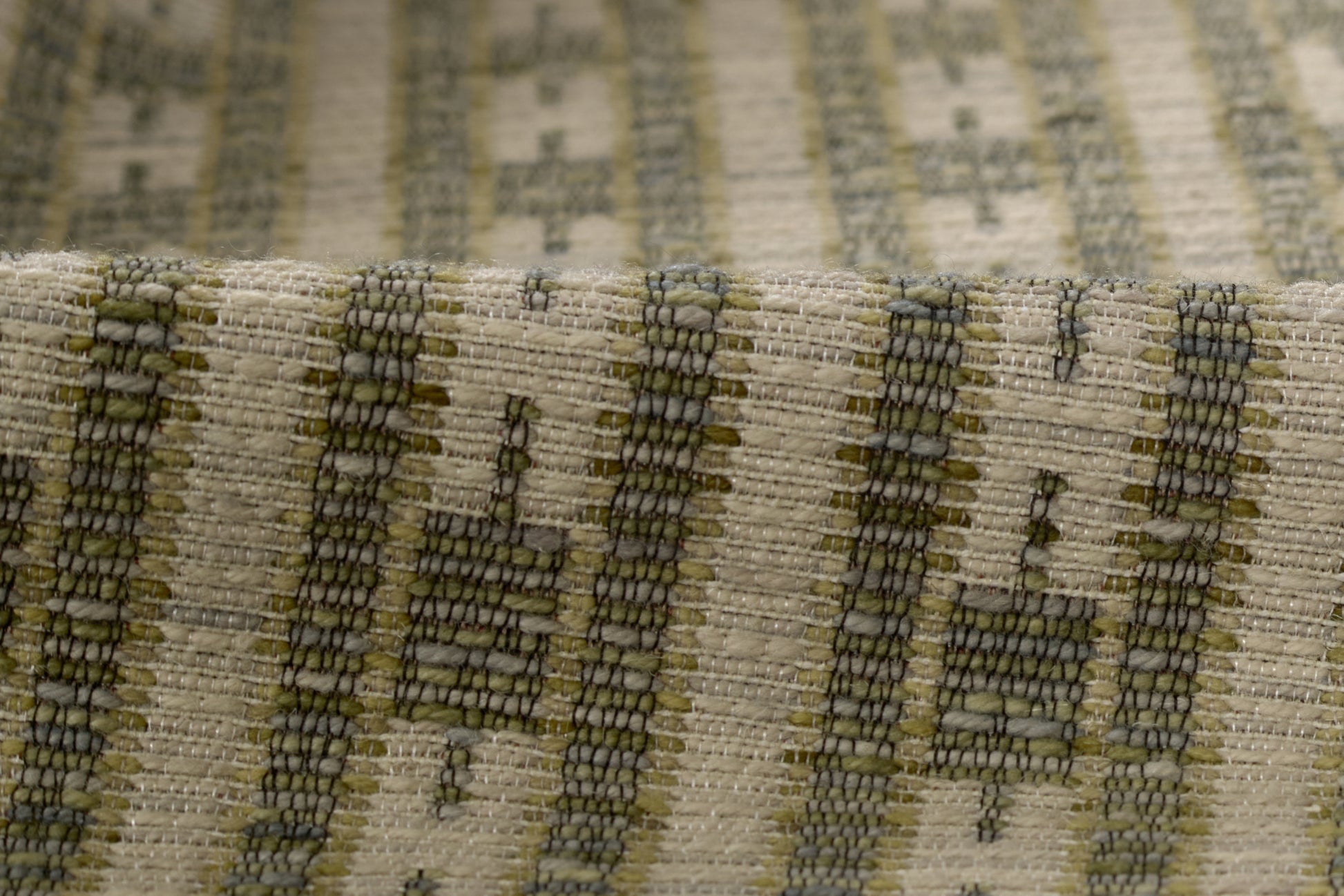 Close-up of woven beige fabric with olive green and dark gray striped geometric pattern; rustic textured rug runner for the floor.