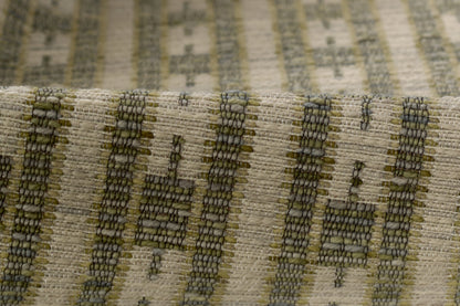 Close-up of woven beige fabric with olive green and dark gray striped geometric pattern; rustic textured rug runner for the floor.