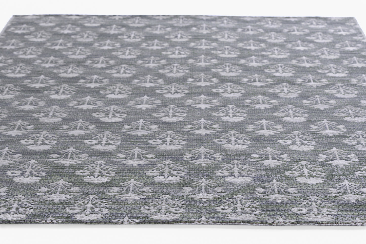 Gray flat-weave rug with repeating white tree-like motifs; rectangular, modern home decor.